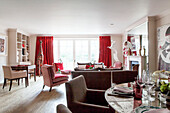 Offener Ess- und Wohnbereich mit roten Vorhängen in einem modernen Haus in London, England, UK