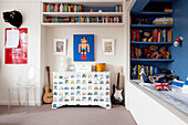 Decorated blanket box and shelves in blue bedroom of contemporary London family home England UK