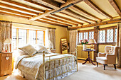 Messing-Doppelbett im gelben Balkenschlafzimmer einer umgebauten Scheune in Surrey England UK