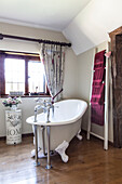 Freestanding bath with towel rack at window of Surrey barn conversion England UK