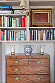 Gilt framed picture and books with wooden chest of drawers in Wiltshire country house England UK