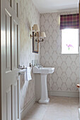 Pedestal basin with wall sconce at window in Wiltshire country house England UK