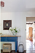 Milk pail and basket with blue painted table in hallway of Surrey cottage England UK