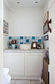 Circular wash basin with blue tiled splashback in bathroom of Surrey cottage England UK