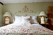 Matching lamps with decorative metalwork above bed in Ripley home West Yorkshire England UK