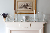 Glassware and silver on white mantlepiece with gilt framed artwork in Chelsea home London UK