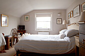 Striped duvet and pillows in room with roller blind at window contemporary Chelsea home London UK