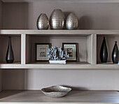 Metallic vases and bottles with artwork on shelving unit in in Lakes home, England, UK