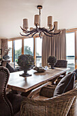 Candelabra above dining table with wicker chairs in Lakes home, England, UK