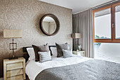 Circular mirror above double bed in Lakes home, England, UK