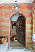 View from brick porch through arched wooden front door of Haslemere home, Surrey, UK