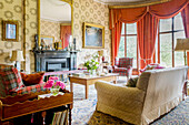 Drawing room with red curtains and south facing windows in historic Somerset country house UK