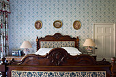 Carved mahogany bed and floral curtains in historic Somerset country house UK