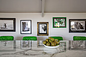 Framed artwork with green bar stools at marble topped kitchen island in Dartmoor farmhouse renovation Devon England UK