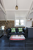 Black Chesterfield and glass-topped coffee table in Dartmoor farmhouse renovation Devon England UK
