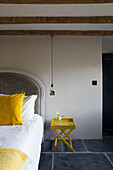 Yellow cushion on bed with velvet headboard in Dartmoor farmhouse renovation Devon England UK