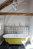 Small yellow freestanding bath and tiled shelf with candles in Dartmoor farmhouse renovation Devon England UK