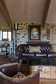 Chesterfieldsessel aus braunem Leder und Glaskasten in einer umgebauten Scheune in Dartmoor, Devon, England, UK