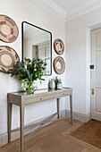 Decorative plates and mirror with flowers at front door in London home UK