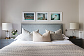 Framed prints above double bed with lamps in London home UK
