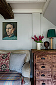 Antique chest of drawers and sofa with artwork in Cirencester farmhouse Gloucestershire UK