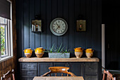 Clock and lanterns with ceramics on sideboard in Cirencester barn conversion Gloucestershire UK