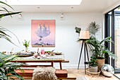 Houseplants and art canvas with table below skylight in dining room of Devon cottage