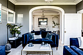 Deep blue velvet two seater sofa with view through arch in double room Clevedon home Somerset, UK