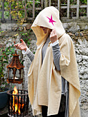 Woman in cloak holding lantern with lit brazier Brighton, East Sussex UK