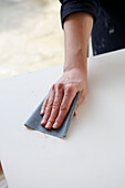 Woman sanding down sideboard in UK home