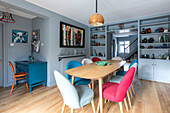 Mehrfarbige Stühle am Esstisch in einem hellblauen Zimmer mit Schreibtisch und Regalen Farnham home UK