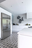 Stainless steel fridge in tiled kitchen with 'The End' neon sign in Farnham home UK