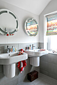 Circular mirrors above double washbasin with colour chart blinds in Farnham home Surrey UK