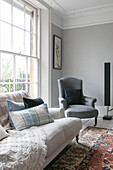 White sofa with checked cushions and grey armchair at window in Winchester home UK