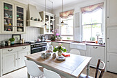 Small pendant lights above kitchen table with sunlight in sash windows of Guildford home Surrey UK