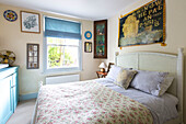 Floral quilt on double bed in with vintage corner cabinet and poster in Reading home Berkshire England UK