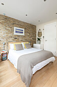 Exposed brick wall in bedroom of converted London courthouse UK