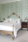 Gold double bed with light green floral wallpaper in Georgian Grade II listed Surrey home UK