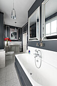 Large mirrors over bath reflect light in bathroom of Victorian terrace Wandsworth London Uk