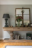 Grey lamp on wooden console with mirror and hydrangeas in Guildford townhouse Surrey UK