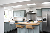 Moderne Küche im Landhausstil mit pastellblauen Schränken und hellen Holzarmaturen
