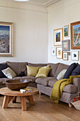 Brown corner sofa with artwork display and wooden coffee table