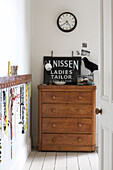 Old fashioned sign and ornaments on wooden chest of drawers