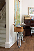 Bicycle with pannier and piano in entrance hall with hanging map