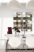 White dining room refracted in mirrored wall installation