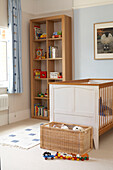 Wooden shelving unit and cot in child's nursery in London home