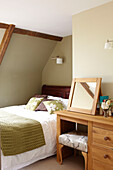 Drassing-Tisch und Spiegel mit Einzelbett im Dachraum einer umgebauten Scheune in Somerset, England, Vereinigtes Königreich