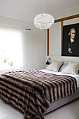 Fur throw on bed in contemporary room with historic oil painting, timber framed Coombe cottage, England, UK