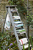 Books stacked on step ladder in walled garden with apple tree, St Lawrence, Isle of Wight, UK