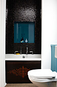 Mosaic tiled bath with niche for toiletries in contemporary Bristol home, England, UK